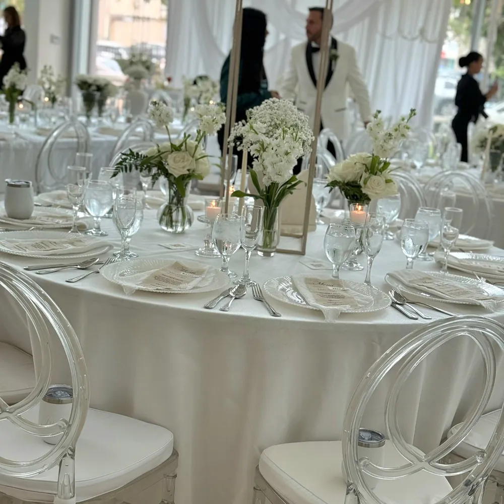 Montaje de boda con mesas vestidas en blanco y cristalería lista