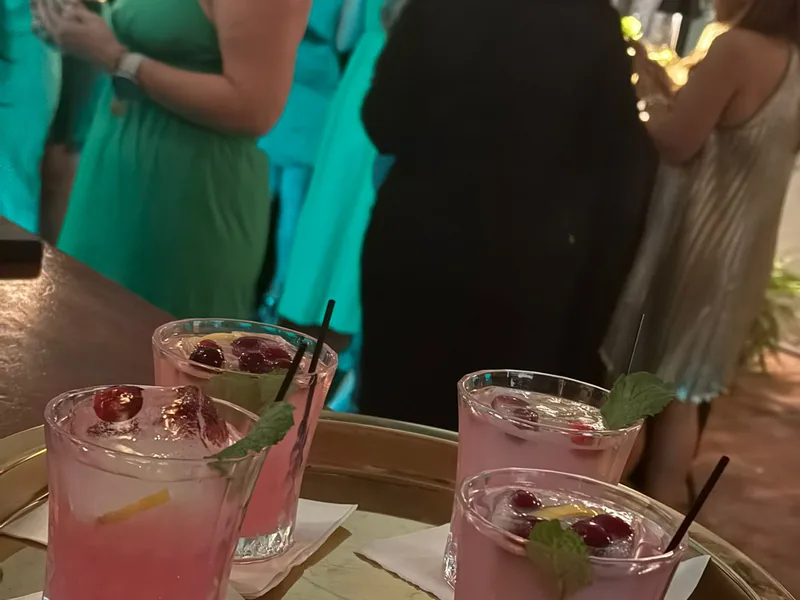 Cócteles servidos en bandeja durante el cóctel de una boda, con las invitadas de fondo