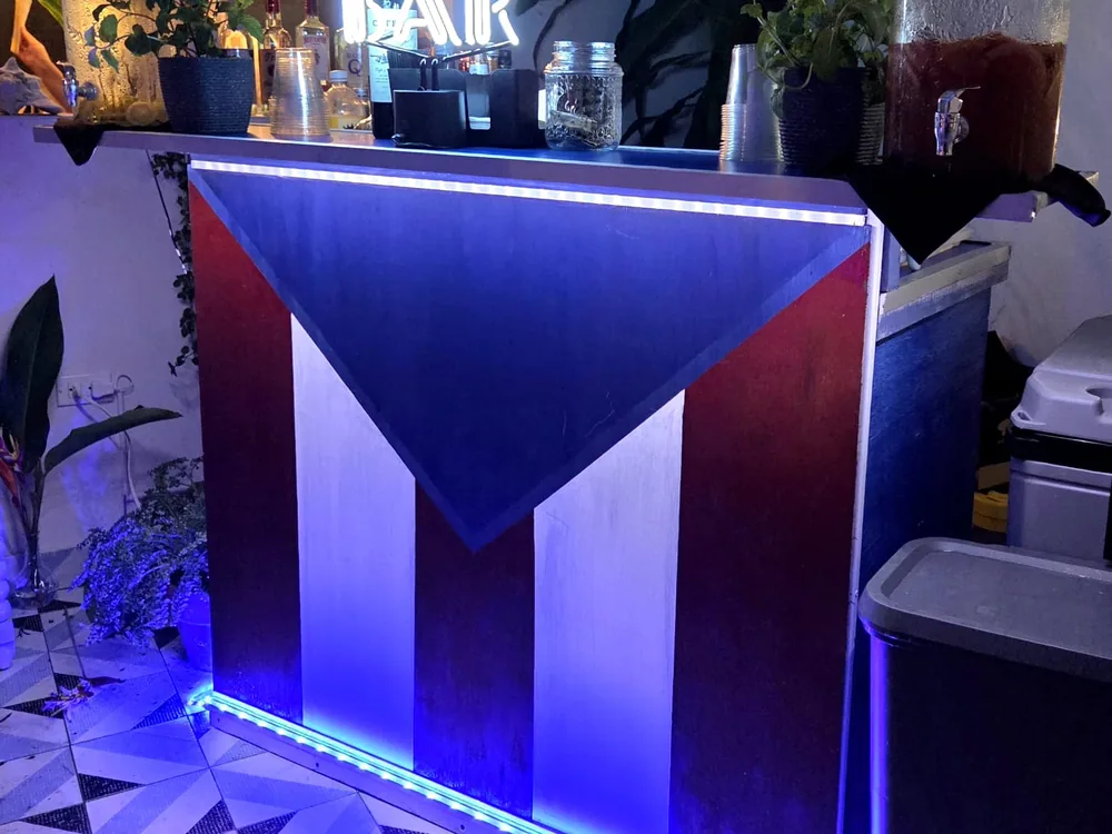 Mojito servido en la barra, con la bandera de Puerto Rico de fondo
