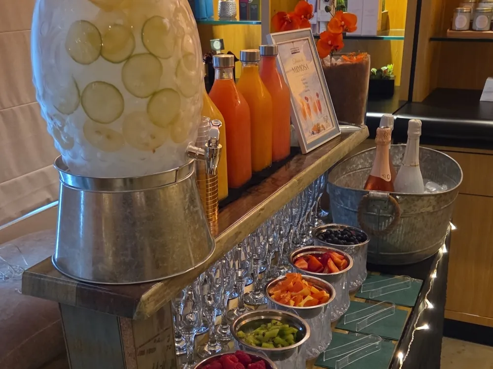 Estación de jugos y mimosas con dispensadores y frutas frescas