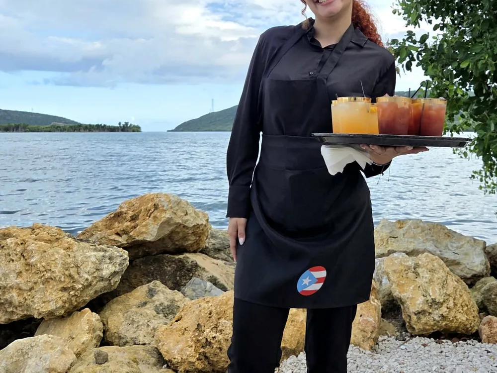 Mesera de Barras Events Group con bandeja de cócteles en un evento junto al mar